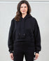 Woman wearing a black hoodie and black pants with white text on a light gray background