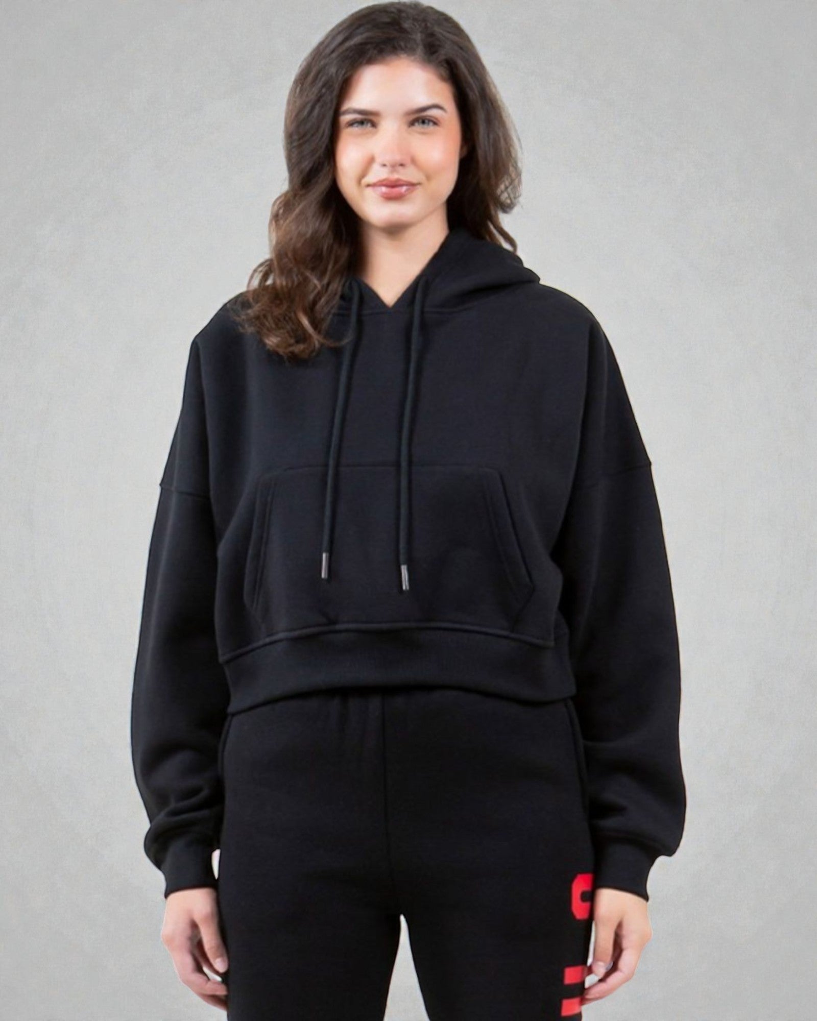 Person wearing a black hoodie and black pants with red accents on a gray background