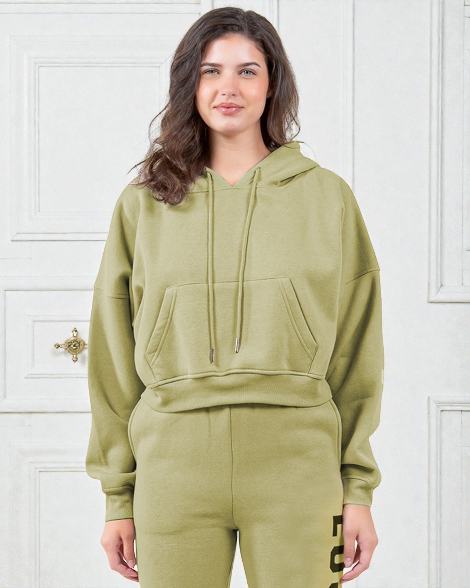 Woman wearing a green hoodie and pants against a white background