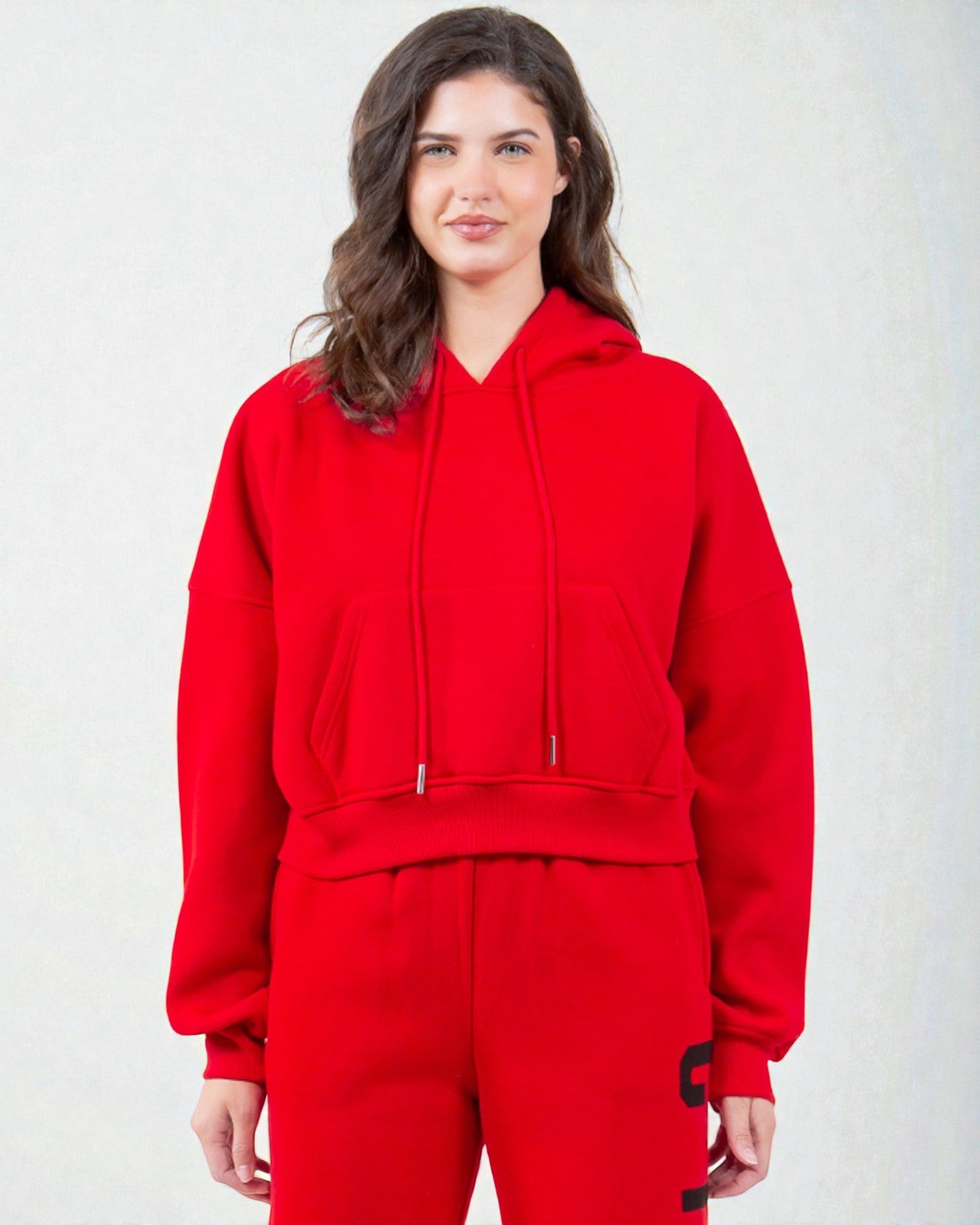 Person wearing a red hoodie and pants on a white background