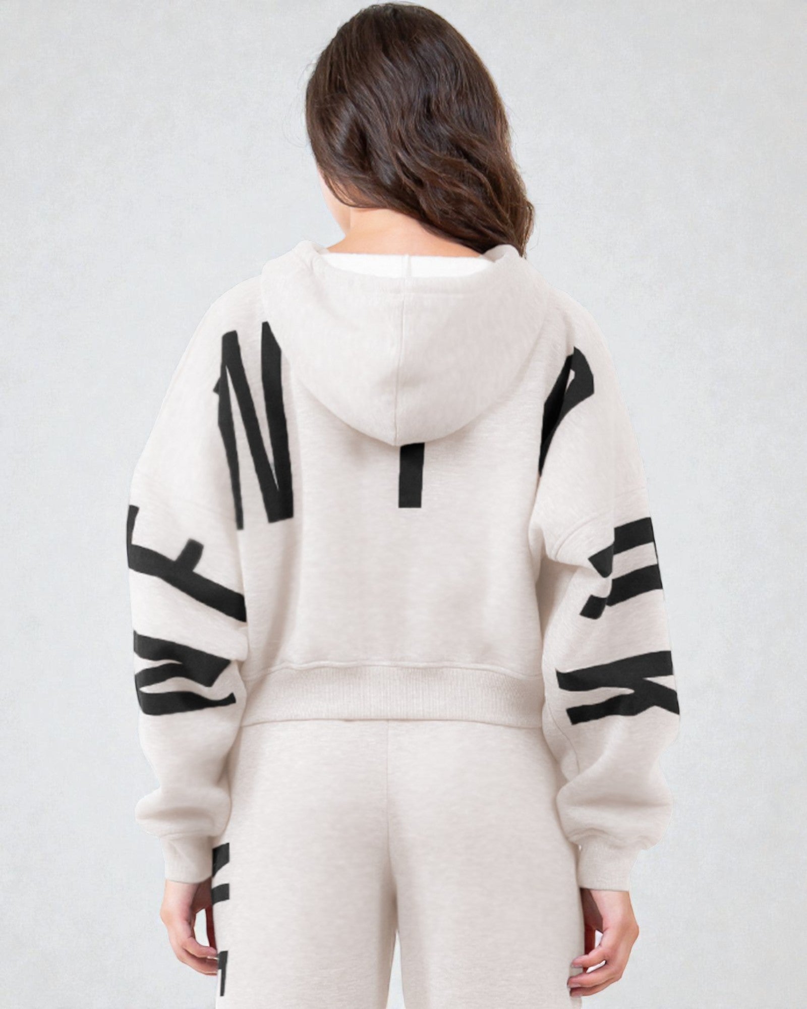 Person wearing a white hoodie with black patterns on sleeves and back against a light gray background