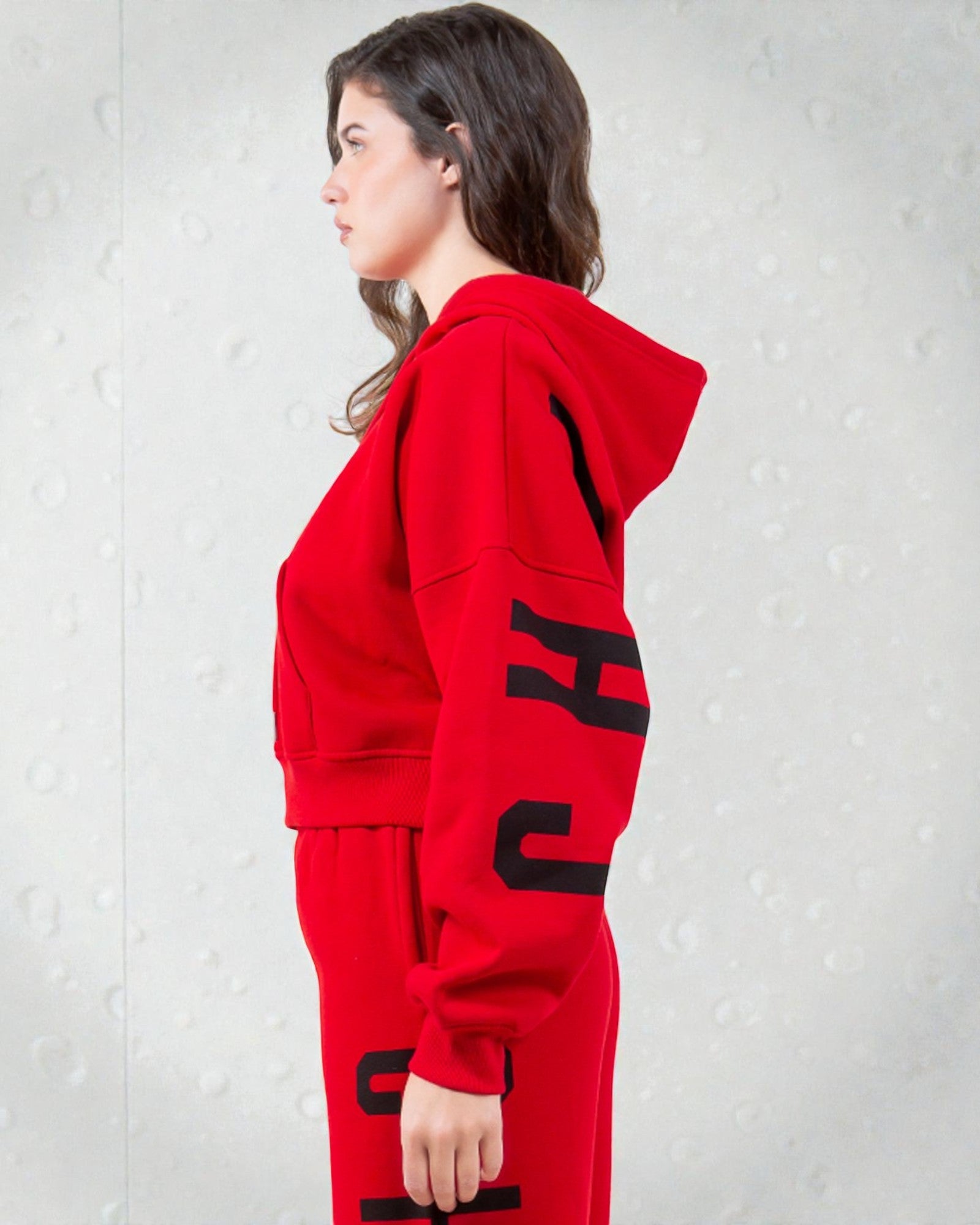 Person wearing a red hoodie with black lettering on a light gray background