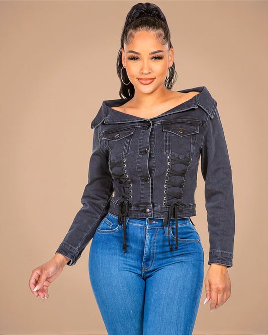 Woman wearing a dark denim jacket with a hood and blue jeans on a beige background