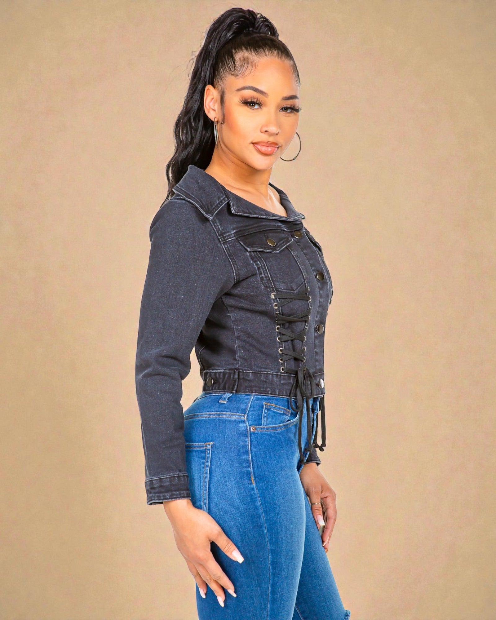 Woman wearing a denim jacket and jeans against a beige background