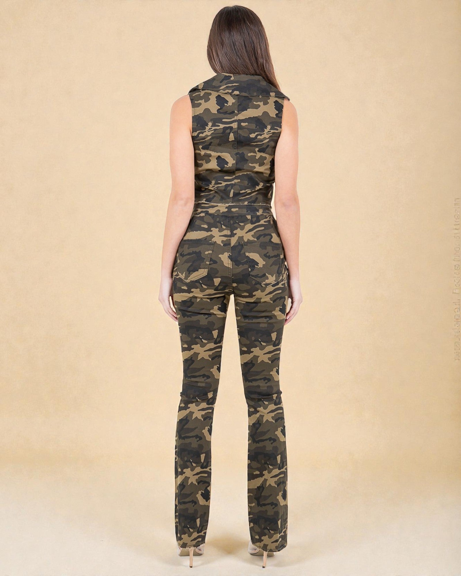 Woman wearing a camouflage jumpsuit against a beige background