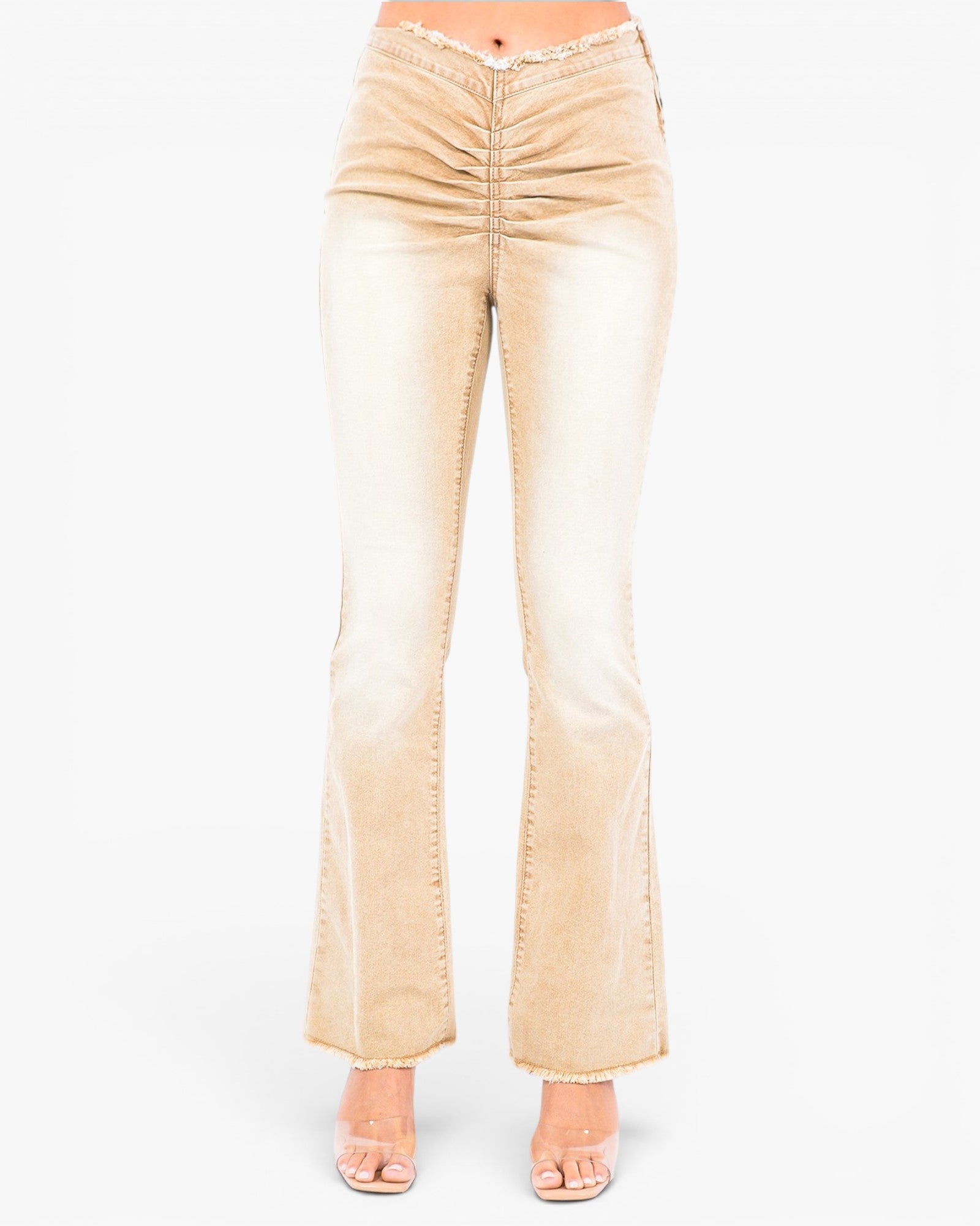 A pair of light beige flared jeans with ruched detailing at the hips, shown on a model from the waist down against a plain white background.