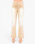 A pair of light beige flared jeans with ruched detailing at the hips, shown on a model from the waist down against a plain white background.