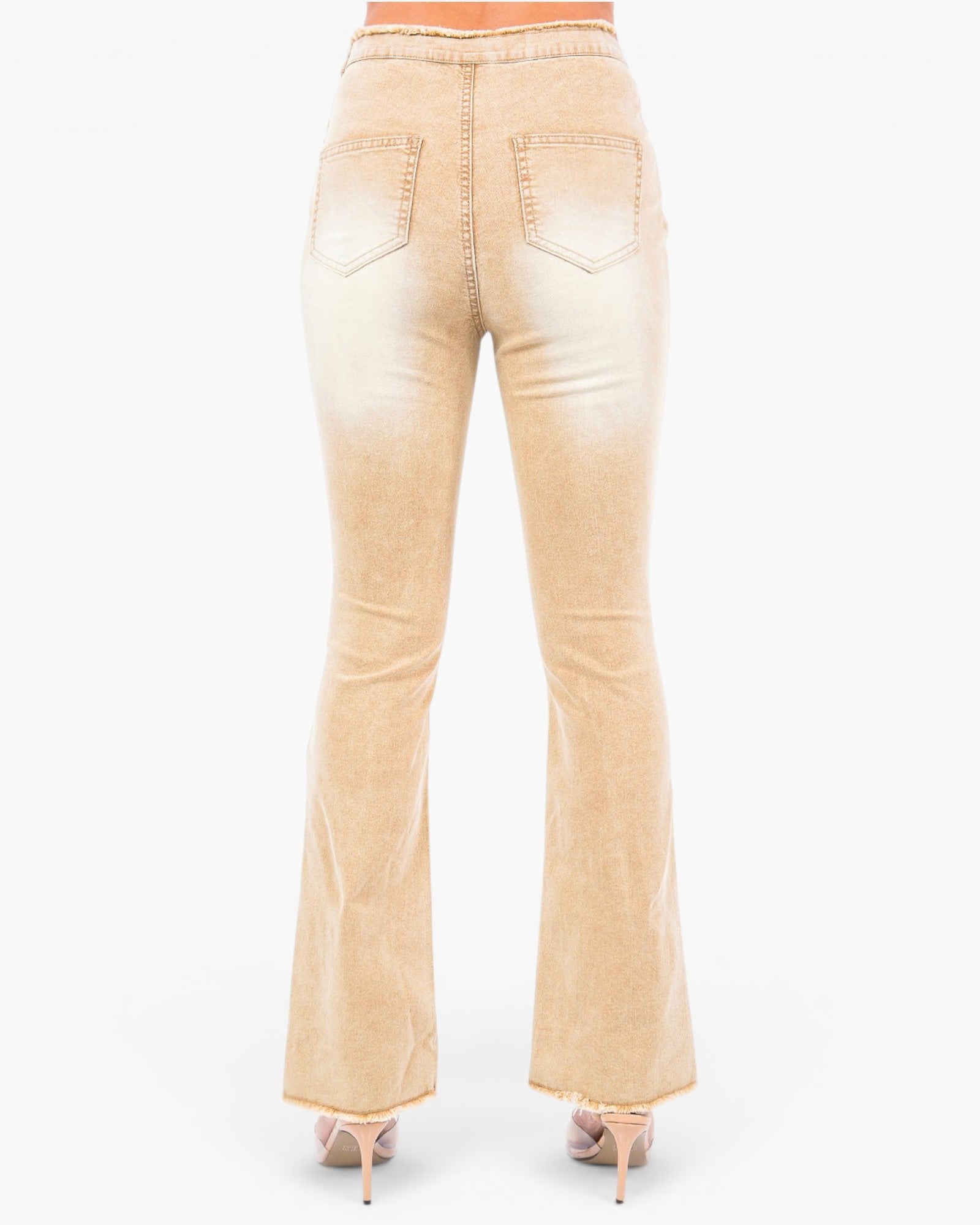Back view of a pair of light beige flared jeans with a faded wash, shown on a model wearing nude high heels against a white background.