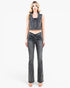 A woman modeling a dark gray washed denim set consisting of a sleeveless cropped vest and matching high-waisted flared jeans with front ruching, against a plain white studio background.