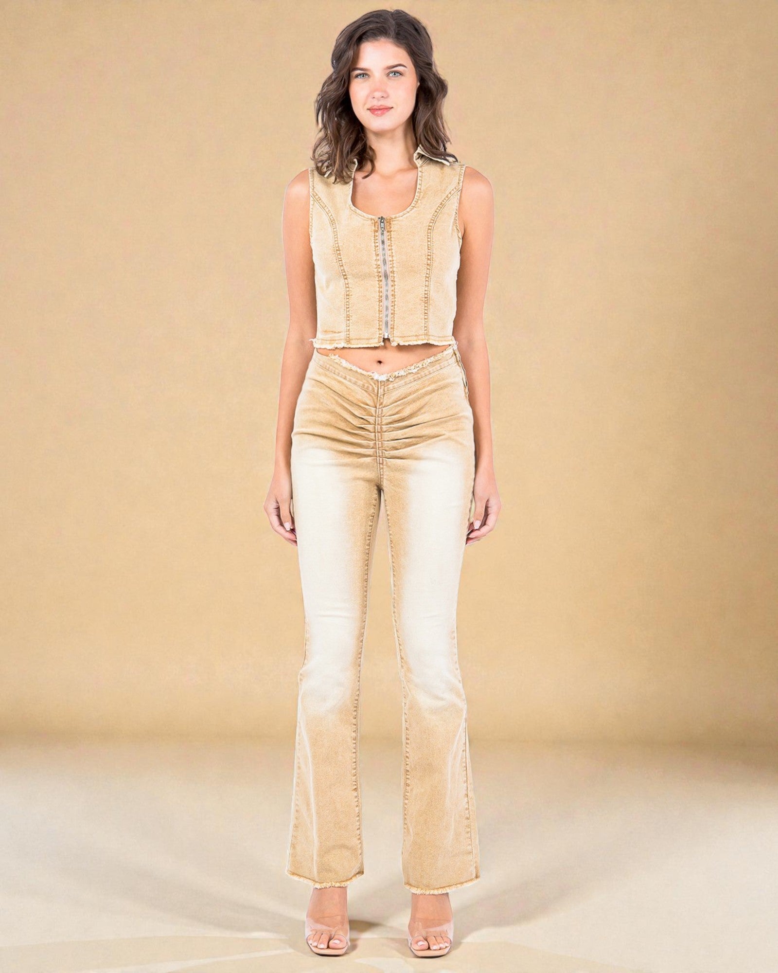 Woman wearing a beige sleeveless top and flared pants against a beige background