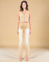 Woman wearing a beige sleeveless top and flared pants against a beige background