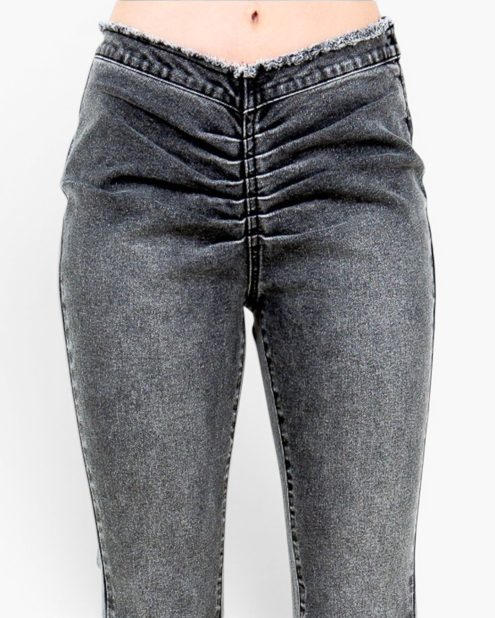 Close-up of a person wearing dark gray washed denim jeans with a ruched front and frayed waistband, shown against a plain light background.