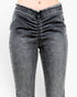 Close-up of a person wearing dark gray washed denim jeans with a ruched front and frayed waistband, shown against a plain light background.