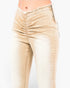 Close-up of a person wearing beige ruched skinny jeans with a frayed waistband and side zipper detail, shown against a plain light background.