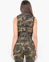 A woman shown from the back wearing a sleeveless camouflage top and jeans against a plain light gray studio background.