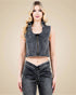 Woman wearing a denim sleeveless crop top and high-waisted jeans on a beige background