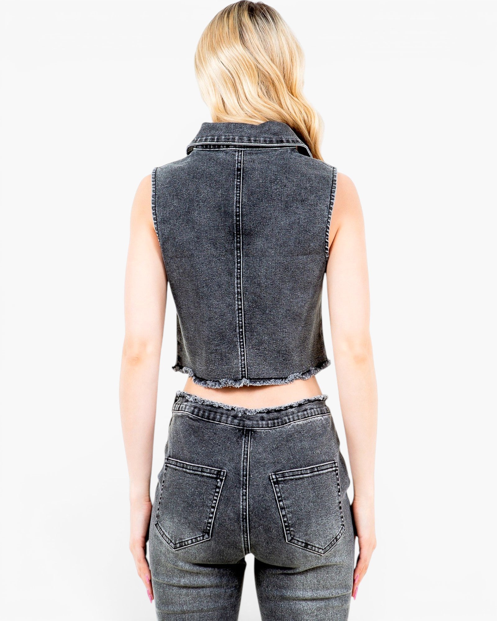 A woman shown from the back wearing a sleeveless dark gray washed denim vest and matching high-waisted denim jeans against a plain white background.