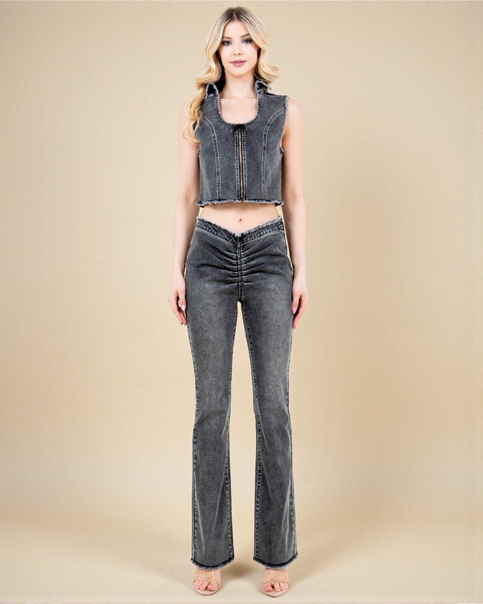 Woman wearing a sleeveless denim top and jeans on a beige background