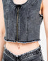 A close-up of a model wearing a cropped gray washed denim top with a front zipper and frayed hem, paired with matching frayed denim bottoms against a plain white background.