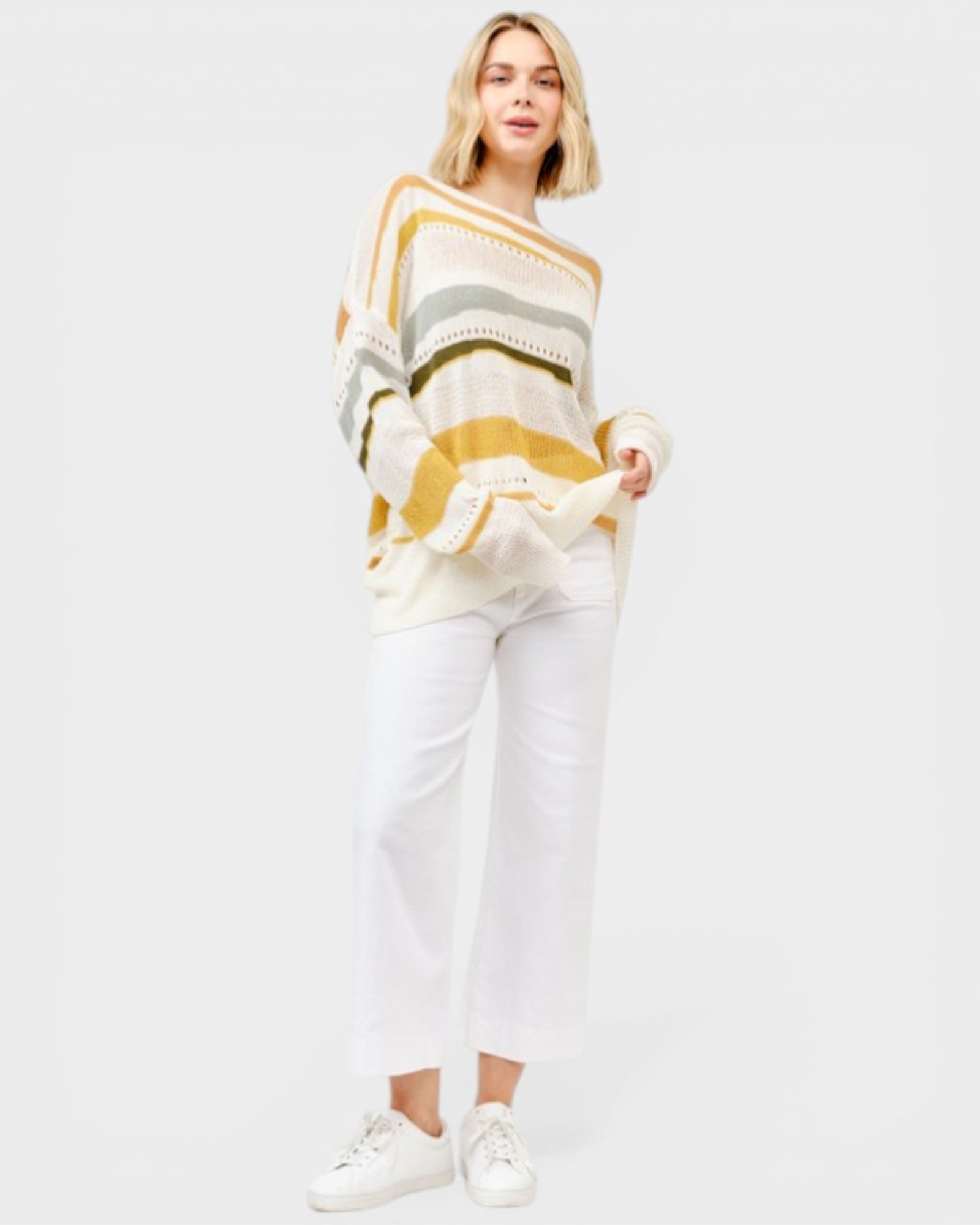 Woman wearing a striped sweater and white pants on a white background