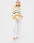 Woman wearing a striped sweater and white pants on a white background