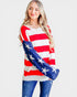 Woman wearing a red, white, and blue striped sweater with star patterns on a plain background