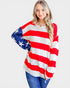 Woman wearing a red, white, and blue striped sweater with star pattern on a plain background