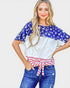 Woman wearing a colorful top with American flag design and blue jeans on a white background