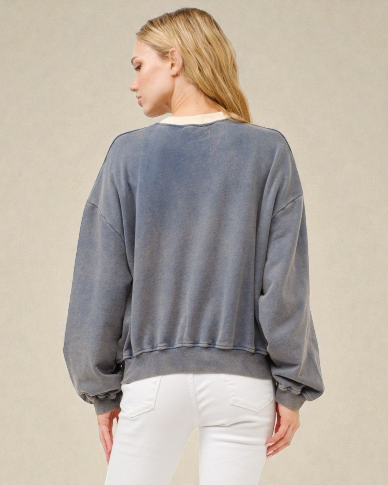 Person wearing a gray sweatshirt and white pants on a beige background