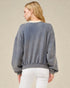 Person wearing a gray sweatshirt and white pants on a beige background