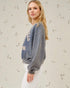 Woman wearing a blue sweatshirt with text on it against a light background