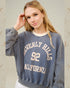 Woman wearing a blue sweatshirt with 'Beverly Hills 92 California' text on a light background