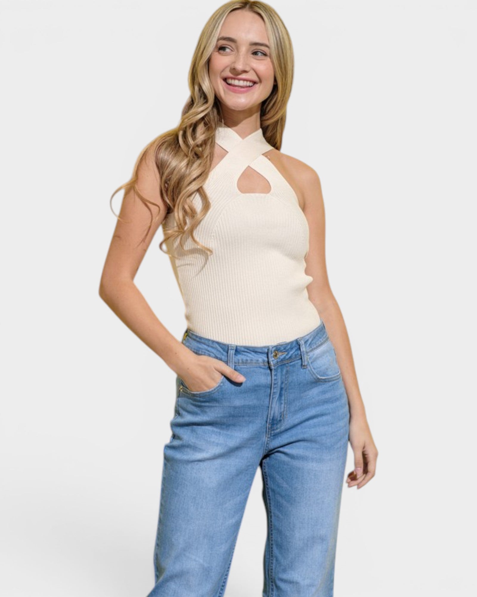 Woman wearing a cream sleeveless top and blue jeans on a white background