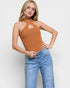 Woman wearing a brown halter top and blue jeans on a white background