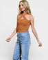 Woman wearing a brown halter top and blue jeans on a white background