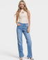Woman wearing a beige sleeveless top and blue jeans on a white background