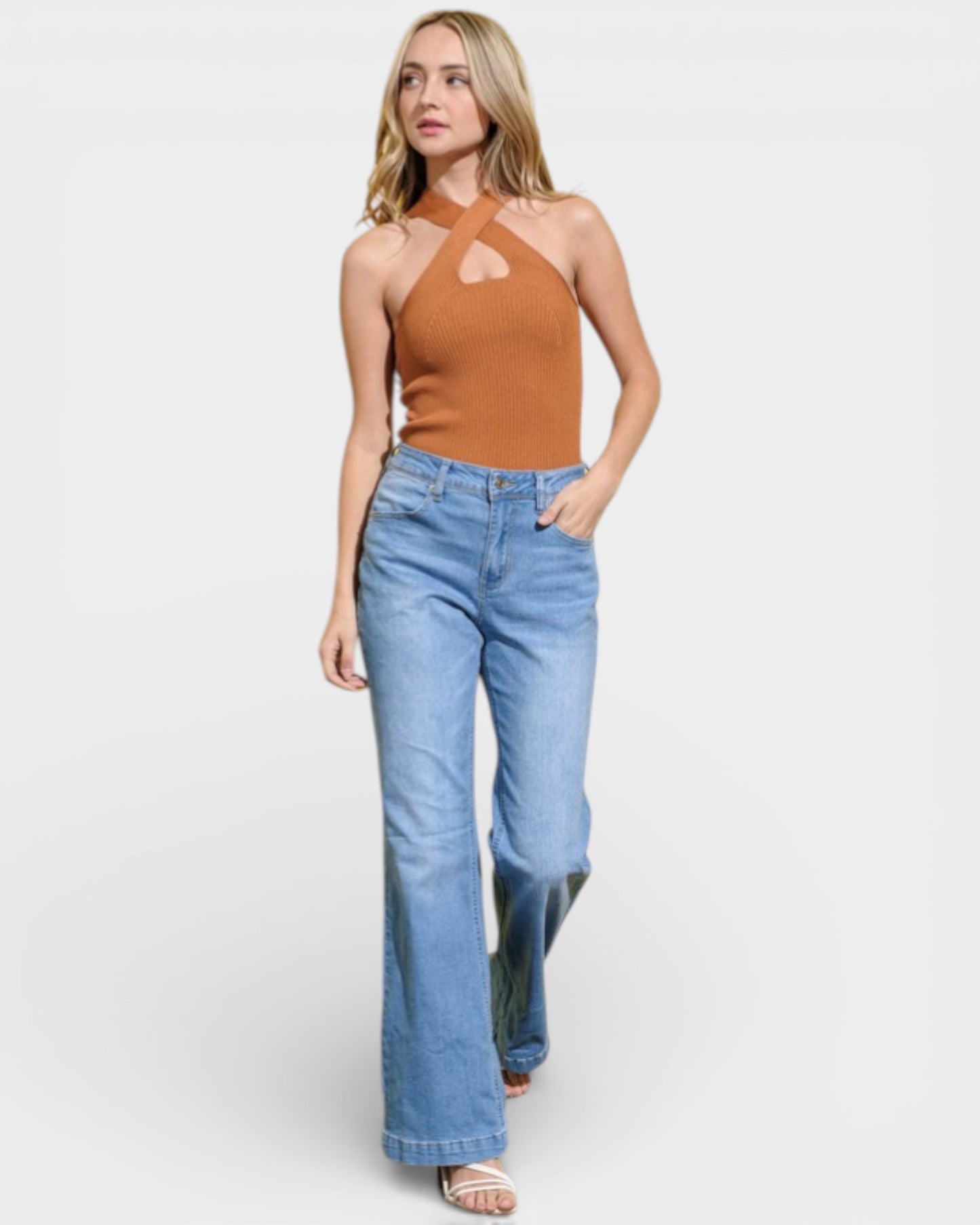 Woman wearing a brown halter top and blue jeans on a white background