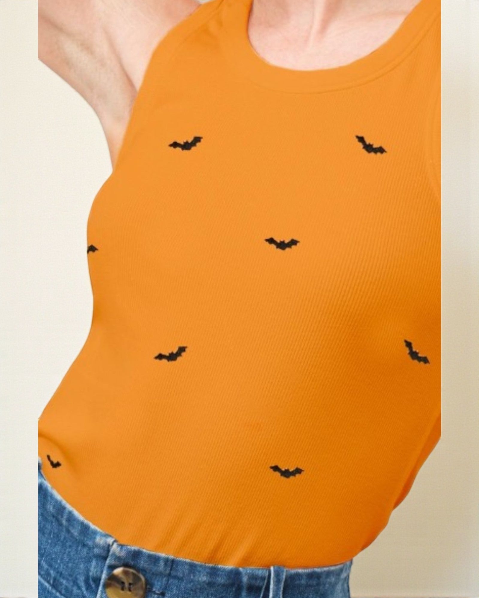 Orange tank top with black bat patterns worn by a person, on a beige background