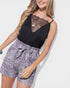 Woman wearing a black lace top and gray floral shorts on a white background