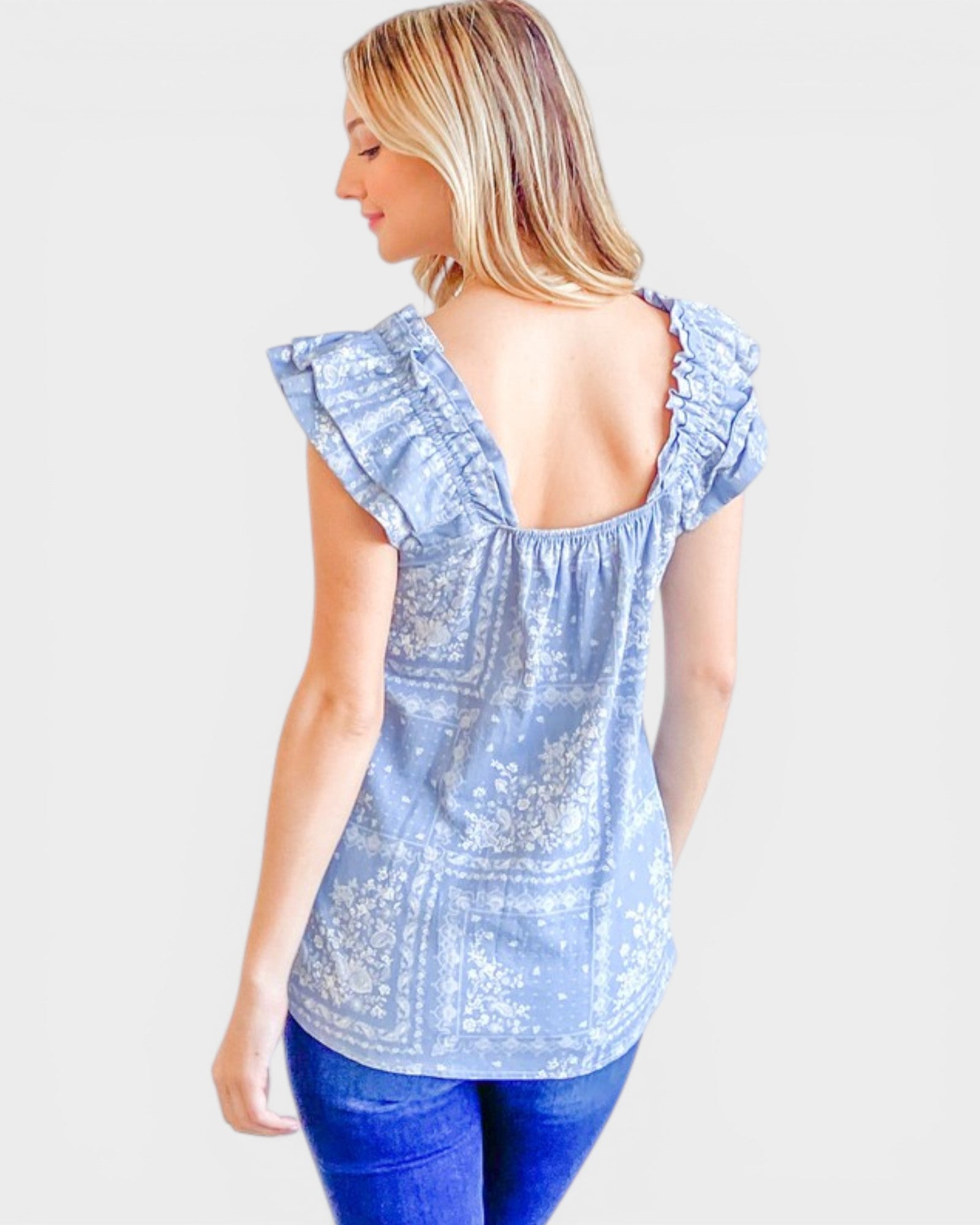 Woman wearing a light blue lace top with ruffled sleeves on a white background
