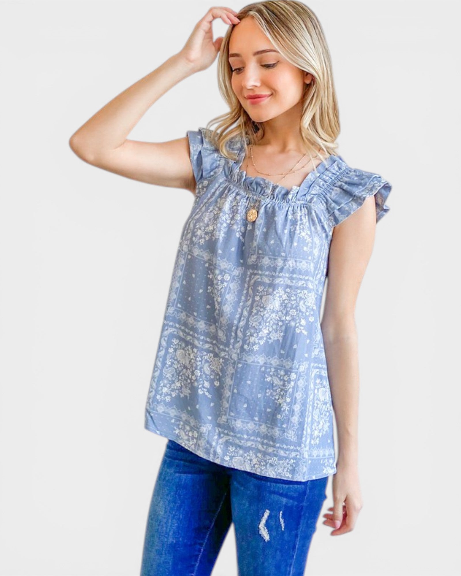 Woman wearing a light blue floral top and blue jeans on a white background