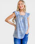 Woman wearing a light blue patterned top and jeans on a white background
