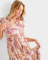 Woman wearing a patterned dress against a plain background