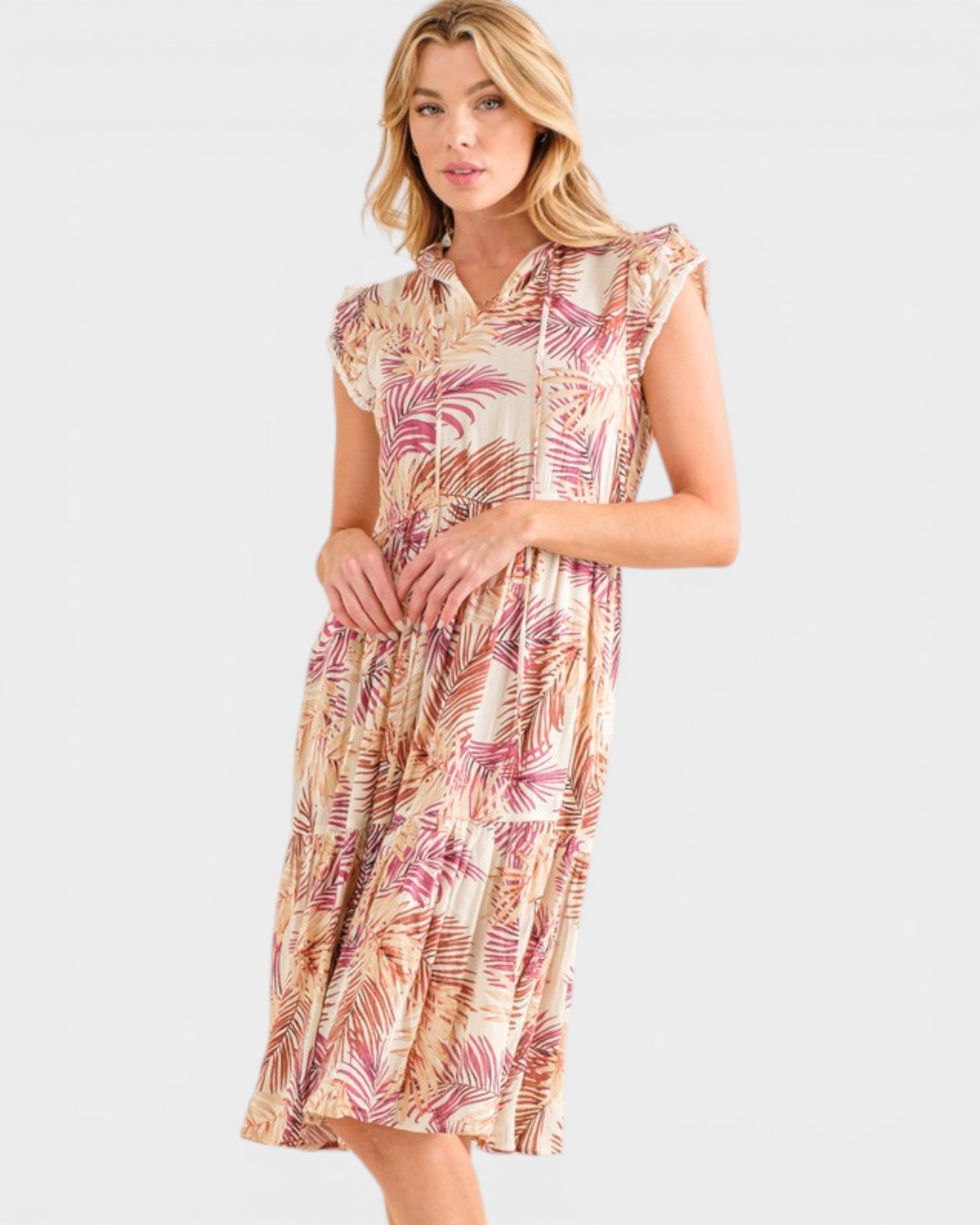 Woman wearing a sleeveless dress with a tropical leaf pattern on a white background