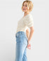 Woman wearing a white t-shirt and light blue jeans on a plain background