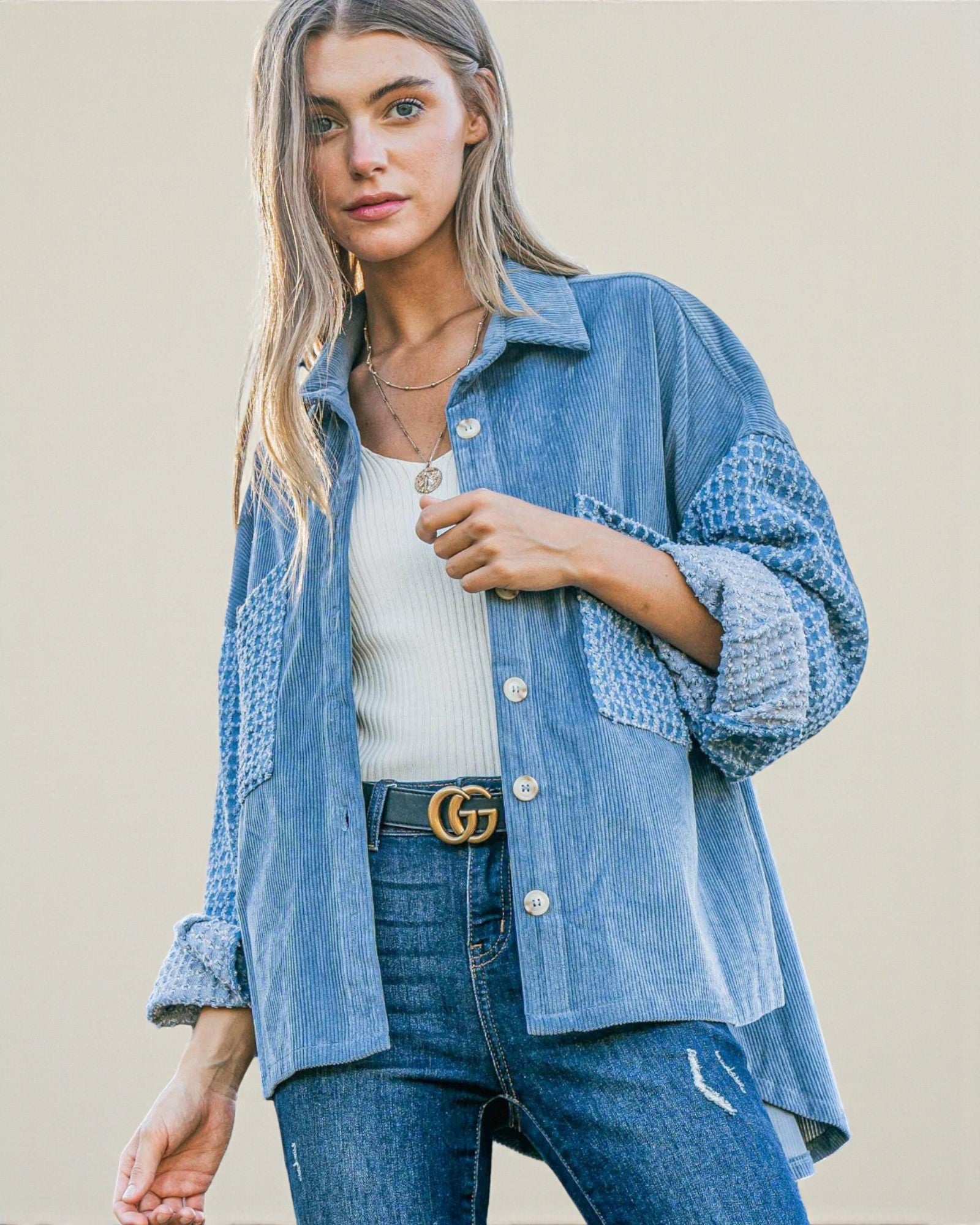 Woman wearing a blue denim jacket and jeans with a beige background
