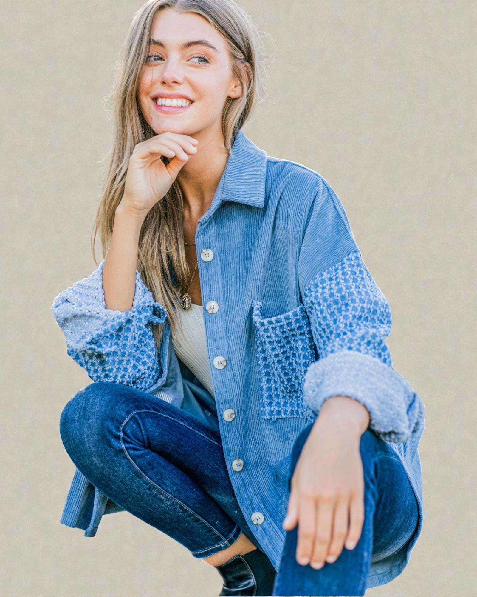 Woman wearing a blue denim jacket with textured sleeves against a beige background