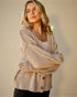 Woman wearing a beige cardigan against a plain background