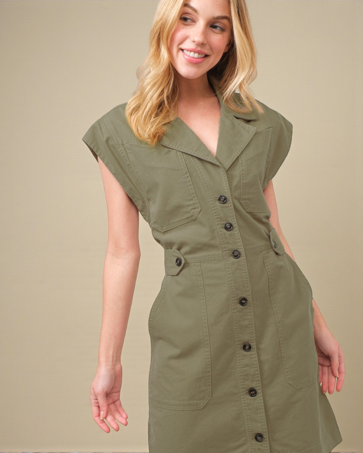 Woman wearing a green dress with buttons on a beige background