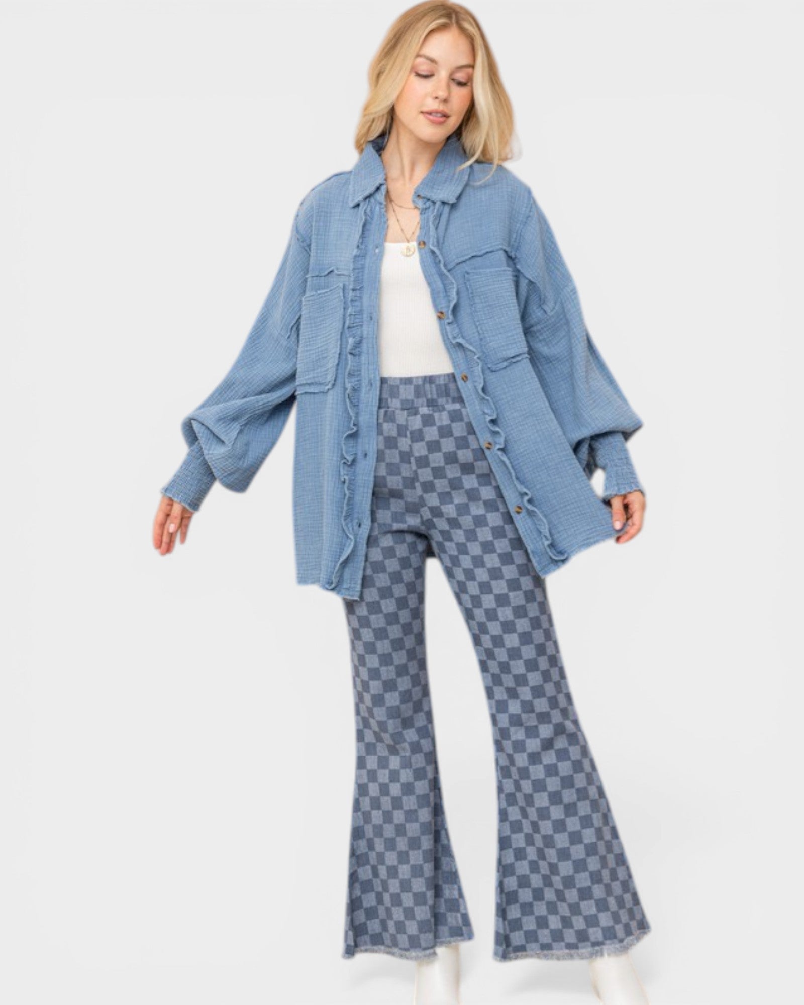 Woman wearing a blue denim jacket and checkered flared pants on a white background